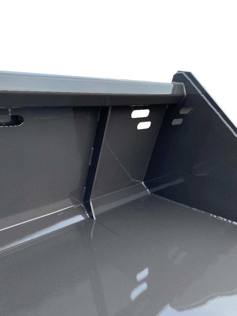 Close-up view of the interior corner of a black metal container with smooth, angular surfaces and a reflective finish, reminiscent of the precision seen in the Skid-Steer Snow Bucket – Utility.