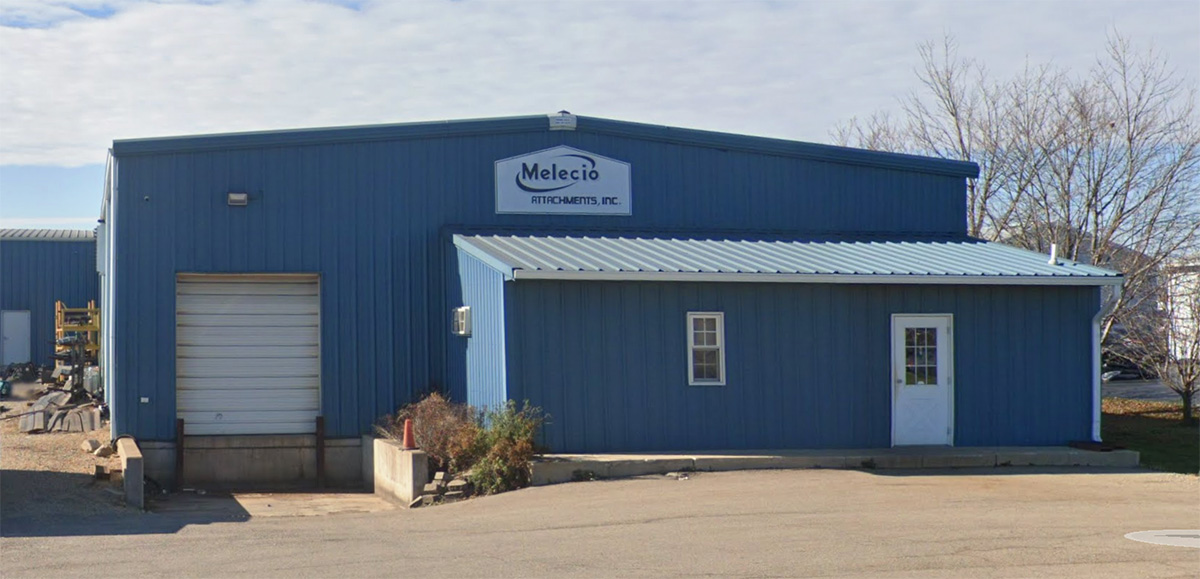 A blue building with a sign that reads "Melecio Attachments, Inc." stands under a partially cloudy sky. It features a garage door on the left and a smaller entrance on the right. For inquiries, please contact us through our main entrance.